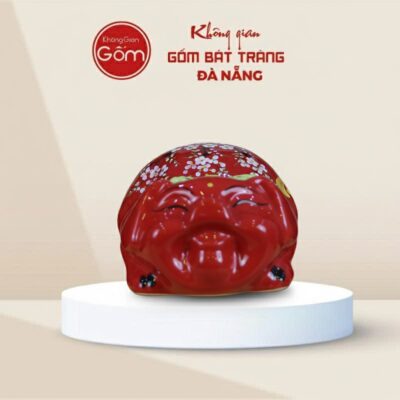 Lợn đất Bát Tràng mắt híp bụng phệ dáng nằm màu đỏ gắn nơ xanh - Ảnh đại diện