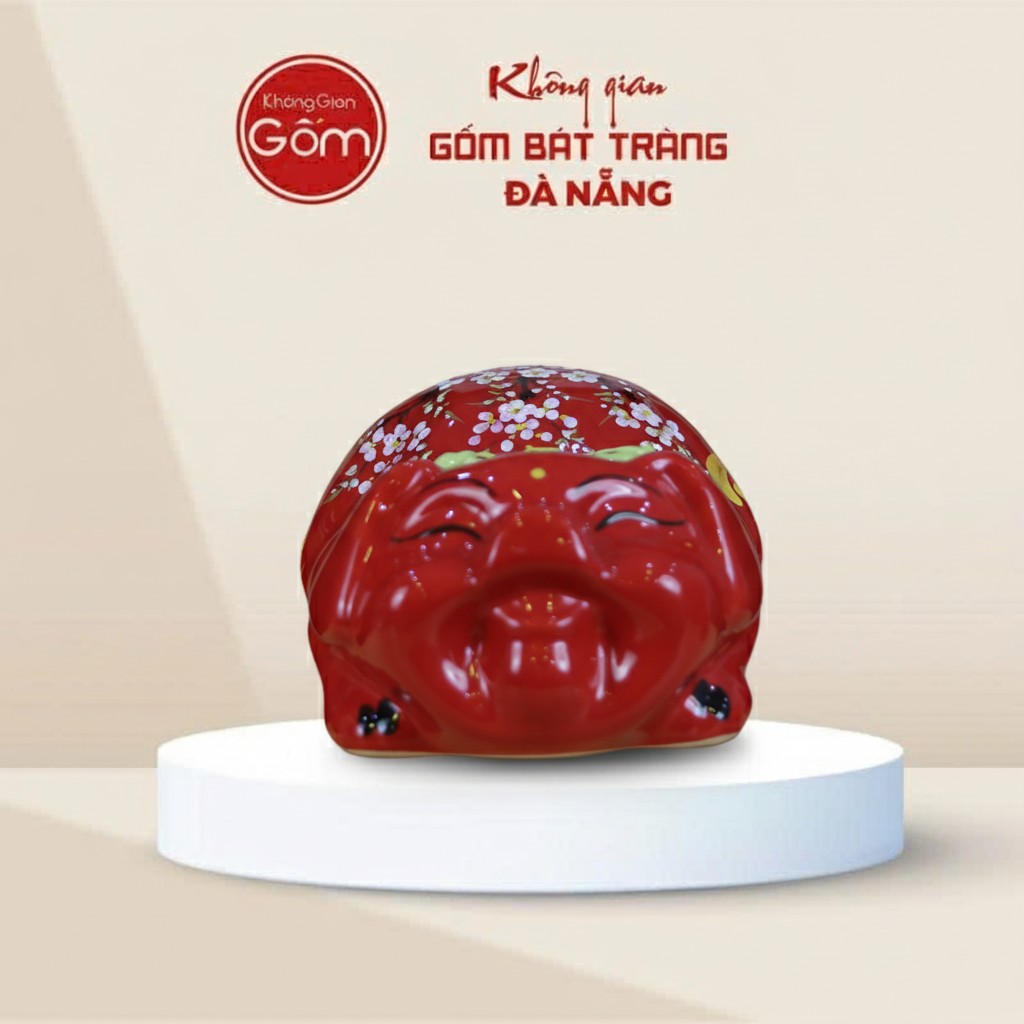 Lợn đất Bát Tràng mắt híp bụng phệ dáng nằm màu đỏ gắn nơ xanh